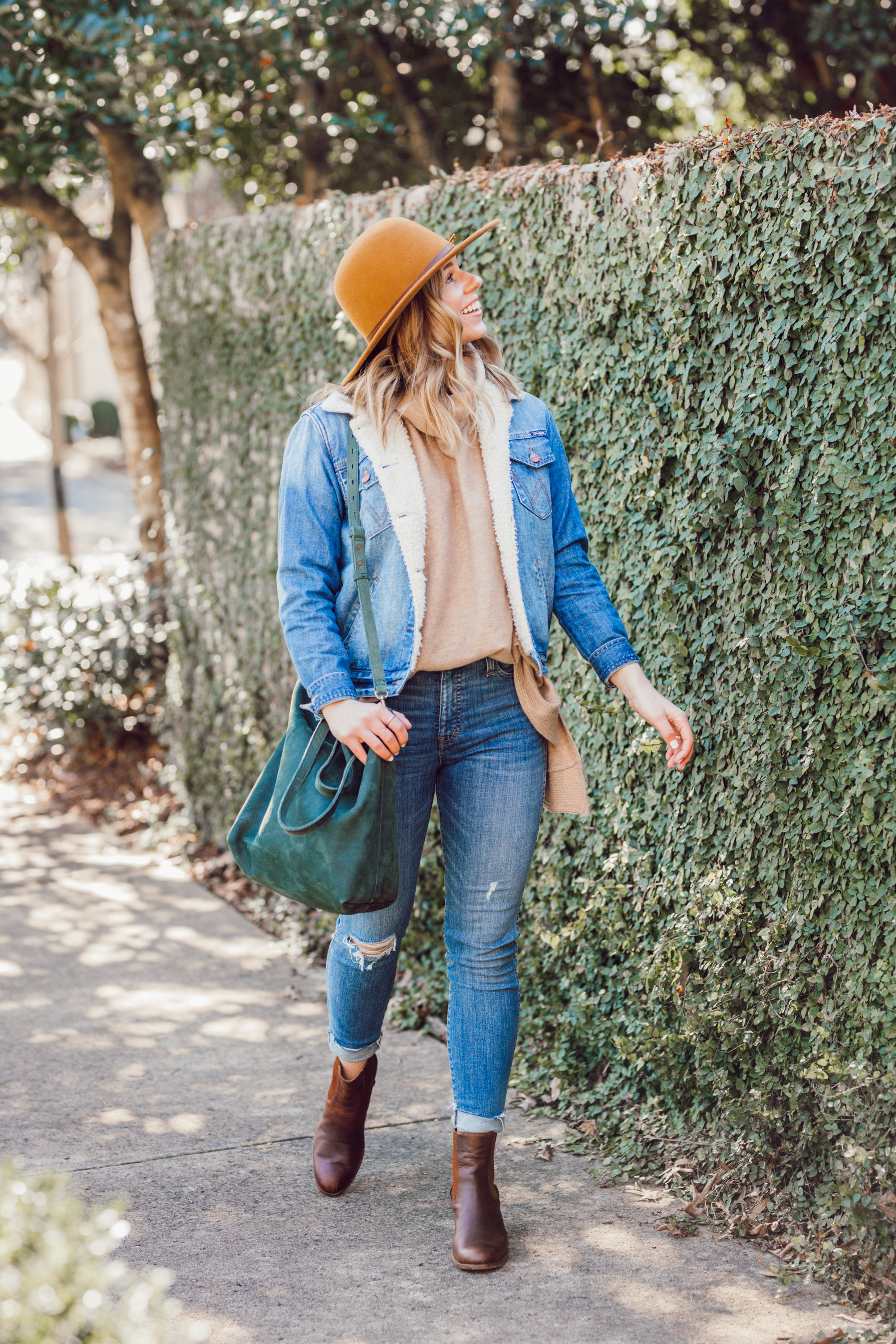 Favorite Winter Boots featured by top US fashion blogger Laura Leigh of Louella Reese; Image of woman sherpa denim jacket, Madewell high-waist skinny jeans, Madewell suede transport tote, Bronze wool hat, Ariat Two24 wilder boots.